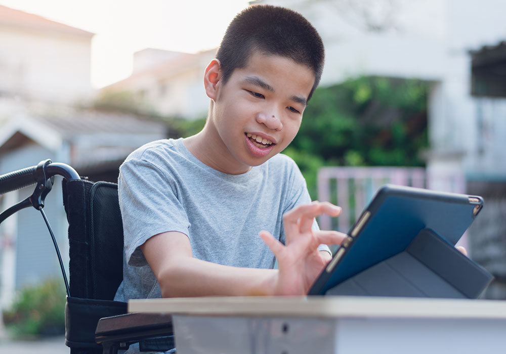 a boy in a wheelchair getting assistanace from a tablet